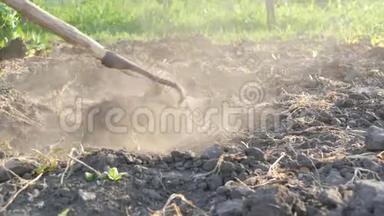 农夫在一块土地上工作。 用花园锄头<strong>挖洞</strong>。 干燥的地面和灰尘。 农业工具