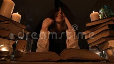 一位无聊的女魔术师在烛光下的一间黑<strong>暗</strong>的房间里特写，涉猎一本书，<strong>沉</strong>思。 低键带电摄像机