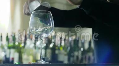手里拿着勺子的家伙慢慢地把冰块加入到酒吧特写的透明酒杯里