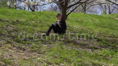 可爱的男孩在公园的草地上<strong>坐在</strong>花<strong>树下</strong>写诗