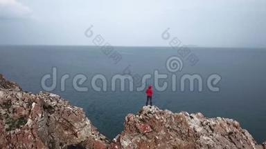 一个女孩站在海边的悬崖边上。 无人机的空中射击。 贝加尔湖。