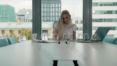 会议室里拿着文件的年轻女商人。 优雅的金发女人坐在现代办公大厅的<strong>长桌</strong>旁