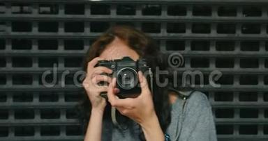 少女在金属围栏前用老式摄像机拍照