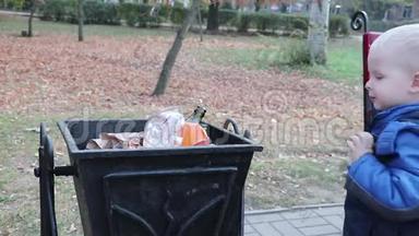 一个小男孩在街上的垃圾桶里扔垃圾。 废物管理和环境保护的理念.. 适当的做法