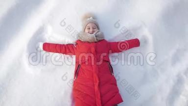 快乐的女孩躺在<strong>雪地</strong>上展示天使。 一个穿外套的漂亮女孩躺在<strong>雪地</strong>上，张开双臂。