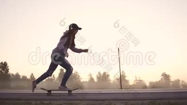 日落时分，一个女孩在一条废弃的高速公路上滑滑板的剪影。 慢动作。