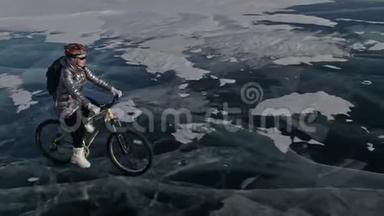 女人在冰上骑自行车。 女孩穿着银色<strong>羽绒服</strong>，自行车背包和头盔。 射击