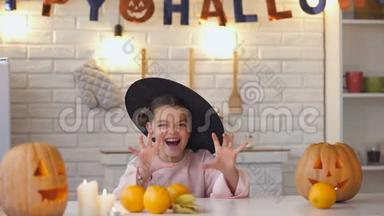 穿着恐怖女巫服装的小女孩从桌子底下跳下来，万圣节派对