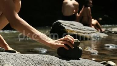 女演员在游客的背景下，在一条山河上的鹅卵石上站着一个凯恩的特写镜头，塔
