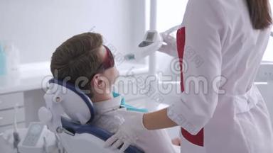 戴着红色防护眼镜的年轻人在牙医那里接受紫外线美白