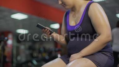 肥胖不健康的女人，有大肚子检查智能手机应用程序<strong>健身</strong>房，<strong>减肥</strong>