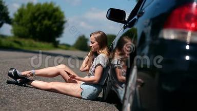 一个金发女孩坐在她那辆破车旁边的马路上