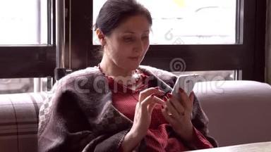 女人在智能手<strong>机上</strong>使用应用程序，在咖啡馆里喝咖啡，微笑着在手<strong>机上</strong>发短信。 美丽的多元文化青年