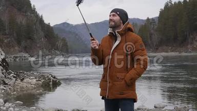 大胡子的游客正在一条<strong>山河</strong>的河岸上用手机播放<strong>视频</strong>。 慢动作