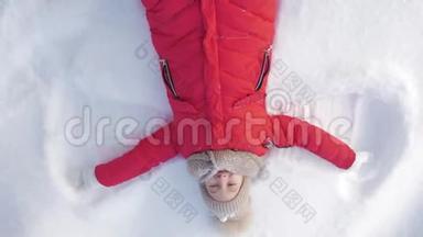 快乐的女孩躺在<strong>雪地</strong>上展示天使。 一个穿外套的漂亮女孩躺在<strong>雪地</strong>上，张开双臂。