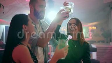 两个女孩和一个男人在俱乐部里玩得很开心，手里拿着眼镜做祝酒词