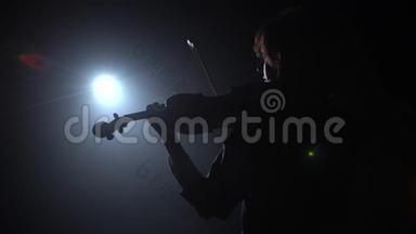 音乐家一边拉小提琴，一边站着，背对着灯笼。 <strong>黑烟</strong>背景。 背面