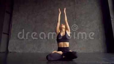 年轻女子坐在莲花姿势练习瑜伽。瑜伽女孩坐在床上，在瑜伽中冥想和举手