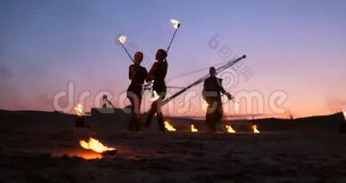 一群男人和女人在夜晚的沙滩上表演火和塔吊的背景