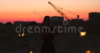 火舞者对抗日落。 在舞蹈表演中，一个年轻的女人用她的火箍在夕阳下摆姿势。