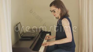 微笑的女人用手提电脑和耳机弹钢琴