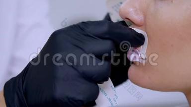 特写镜头，一家美容诊所，医生在注射透明质酸之前将麻醉药`病人的嘴唇上