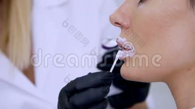 特写镜头，一家美容诊所，医生在注射透明质酸之前将麻醉药`病人的嘴唇上