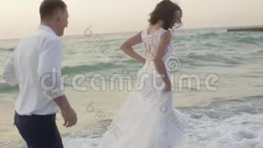 可爱的一对<strong>新婚</strong>夫妇在日落时在海滩上休息。 他们快乐地奔跑和拥抱。 <strong>浪漫浪漫</strong>