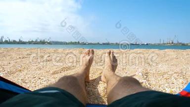 游客躺在海滩上的帐篷里，脚<strong>踩</strong>在沙子上。