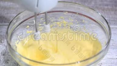 用电动搅拌器在玻璃碗中敲打鸡蛋。