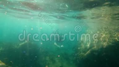 一个年轻人浮潜和潜水潜入海里的慢动作镜头。 在水中显示OK