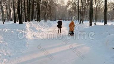 一个穿着<strong>橘色</strong>夹克的女人<strong>和</strong>一个婴儿车在冬季城市公园散步。穿着毛皮大衣的女人。