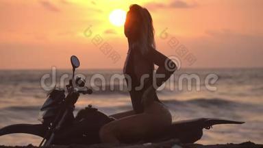 穿比基尼的漂亮模特在<strong>红日</strong>落时坐在摩托车上，双手放在腿上，美丽的日落景色