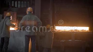 冶金<strong>生产现场</strong>.. 在阴沉的商店里，工人们监视着炉子的运行。 在炉子下面
