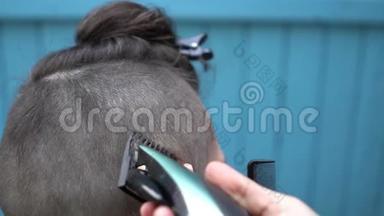 漂亮的女理发师用电动剃须刀<strong>剪开</strong>客户的头发，并用梳子梳回视野