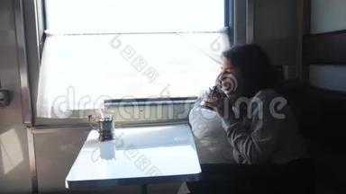铁路旅行概念。 看着窗外的小女孩在车厢里喝茶。 穿深色衣服的女孩喝酒