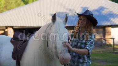 在<strong>炎热的夏天</strong>，一个戴着牛仔帽<strong>的</strong>年轻女孩在动物农场照顾和抚摸一匹马。 慢动作