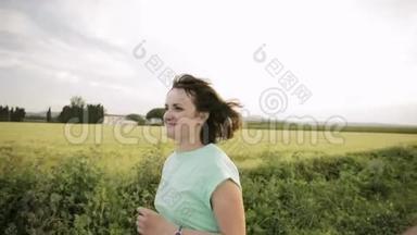 年轻的白种人女孩享受生活，在西班牙农村的道路上慢跑，穿过农村的麦田