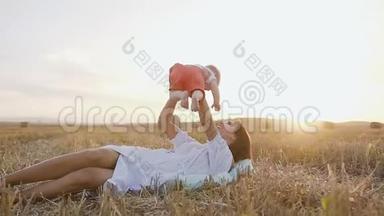 妈妈和小男孩在大自然上快乐地玩耍，躺在田野里的妈妈把小宝宝抱在怀里，在里面放松
