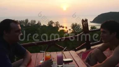 两个商人坐在山上的咖啡馆里，俯瞰大海和令人惊叹的日落，3840x2160