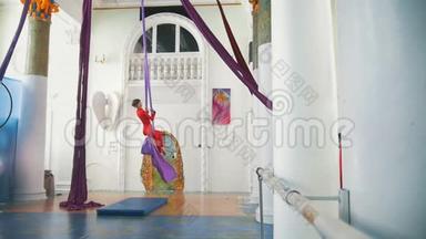灵活的女子空中体操运动员在<strong>排练</strong>厅里用空中丝绸摆动