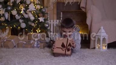 <strong>一个</strong>小男孩打开<strong>一个</strong>装有礼物的盒子，高兴地躺在圣诞树附近的<strong>地板上</strong>