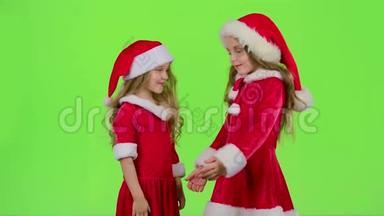 穿红色西装的孩子玩新年`游戏，微笑，玩得开心。 绿色屏幕。 慢动作