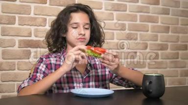 有<strong>胃口</strong>的饥饿少年在阁楼式的厨房里吃一个三明治，里面有新鲜的生菜和西红柿