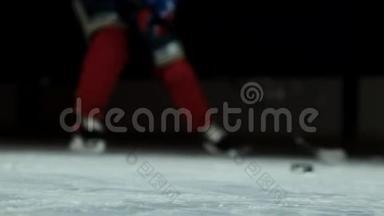 冰球的特写镜头放在冰上，慢动作的曲棍球运动员拉起来，雪飞进照相机，他