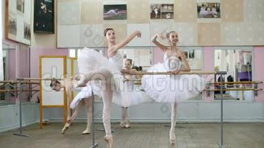 在芭蕾舞厅里，穿着白色芭蕾舞裙的女孩在芭蕾舞中投入，排练姿势，年轻的芭蕾舞演员站在脚趾上