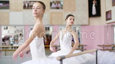 在芭蕾舞厅里，两个穿着白色芭蕾舞裙的女孩在芭蕾舞表演，排练转身，年轻的芭蕾舞演员