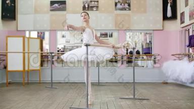 在芭蕾舞厅里，穿着白色芭蕾舞裙的女孩，包在芭蕾舞中，排练带有斜坡的胸罩，Raises的手