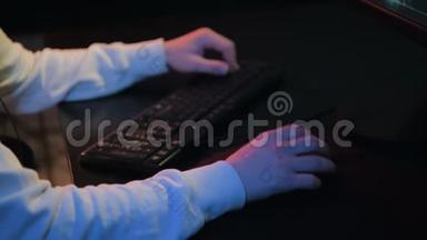 特写男玩家`的手在定制桌面上玩电脑游戏用键盘、鼠标。