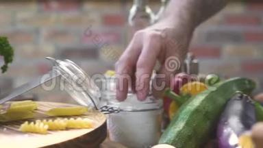 厨师的手拿盐夹取盐腌食品，同时烹饪厨房菜肴。 厨师烹饪腌制食物